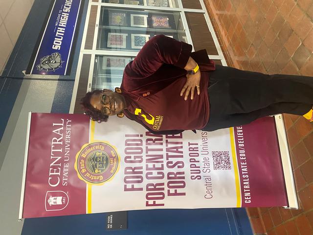 East High School assistant principal Karen Carey beside a large popup banner for Central State University