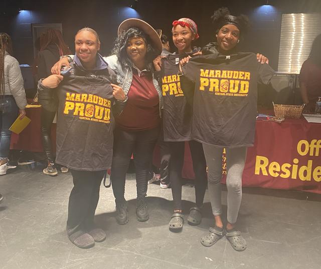 four young people hold Marauder Proud sweaters at a Central State University recruiting event in Columbus, Ohio