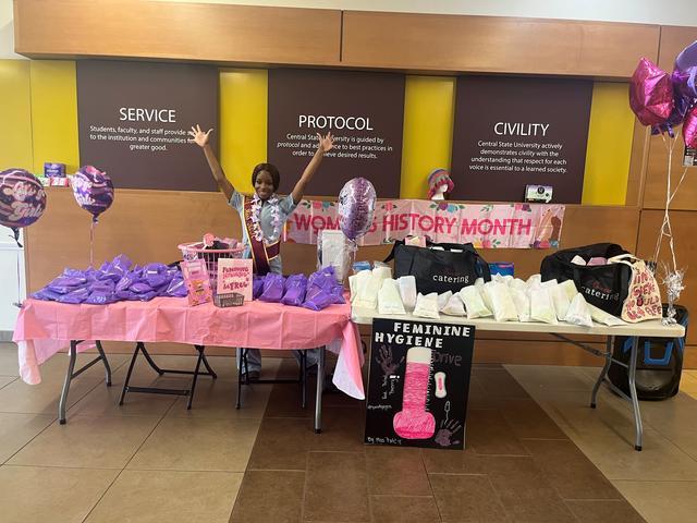 wenese geary sets up at a table full of pink at the central state university student center