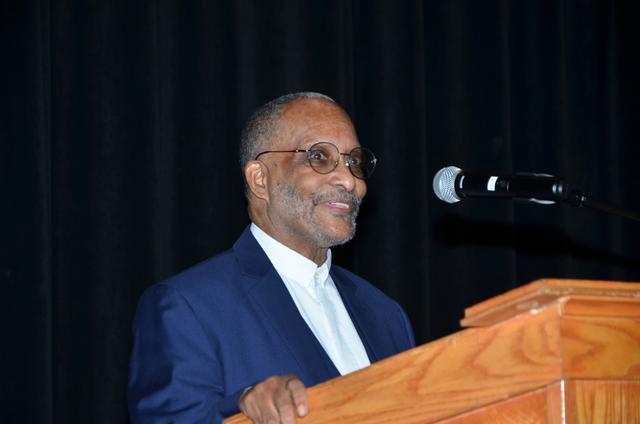an african american man wearing a blue suit speaking at a podium