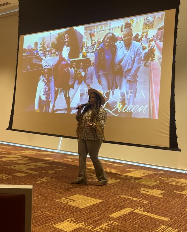 teeya skipper wears a hat in front of a presentation on a large screen