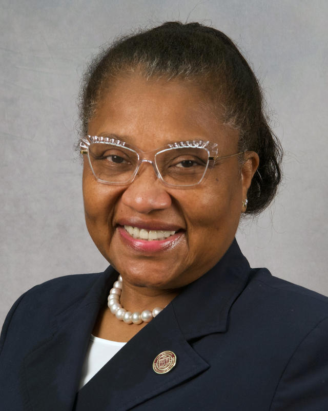 dr. margery coulson-clark wearing a blue suit jacket pearls glasses and a central state university lapel pin