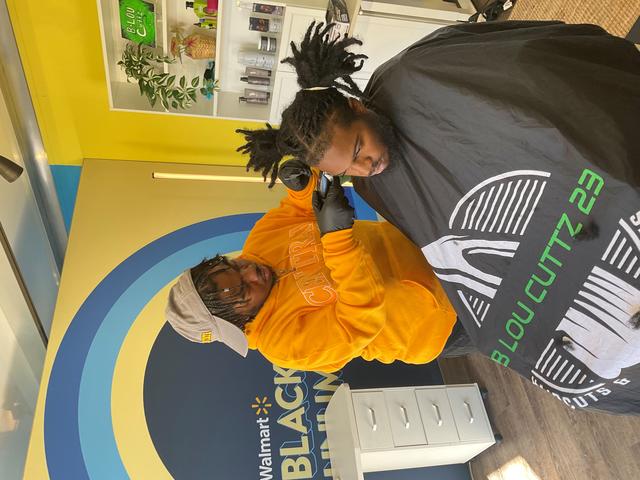 a student gets a haircut during the walmart black and unlimited tour at historically black colleges and universities