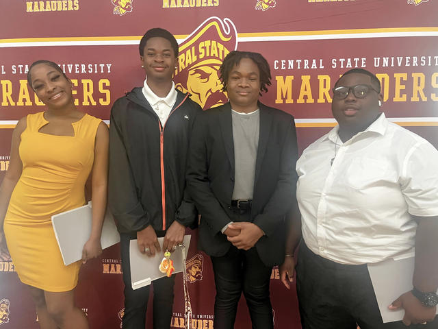 four central state university students in professional dress stand in front of a marauders backdrop