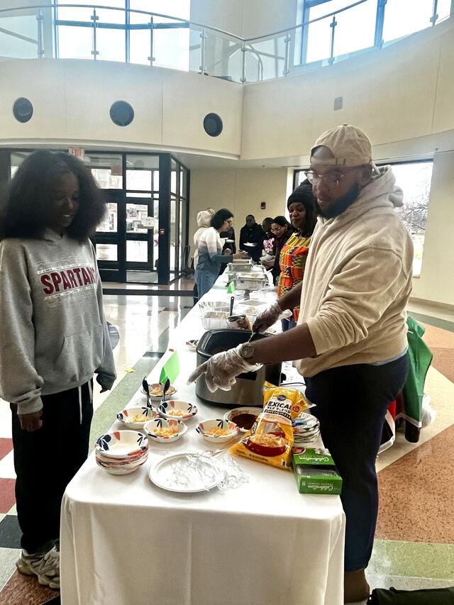 a man serves food to a student at the taste of the world event at central state university