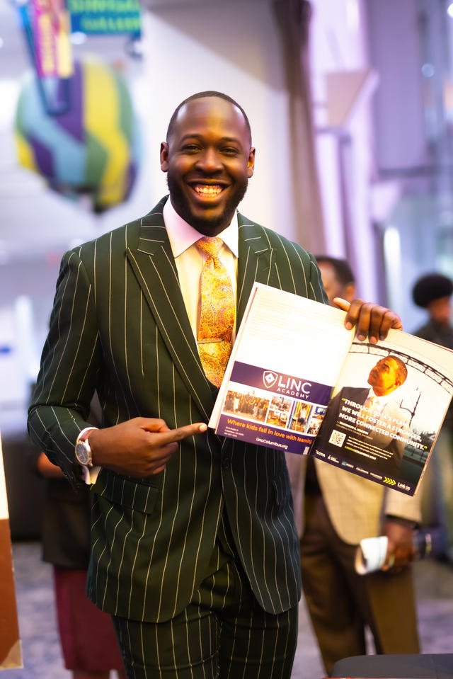 black man in a striped suit holding a magazine open