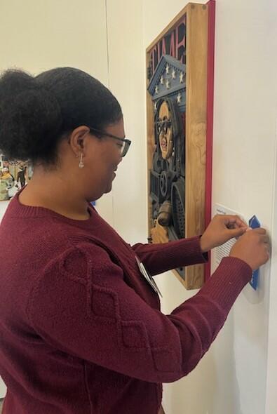 nya brunson places a label on a wall beside art