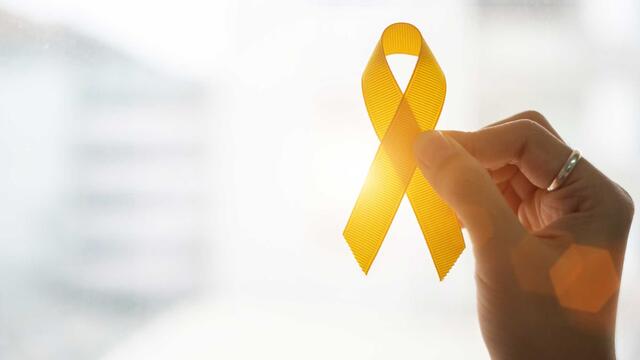 a hand holds a yellow ribbon for suicide prevention awareness counseling at central state